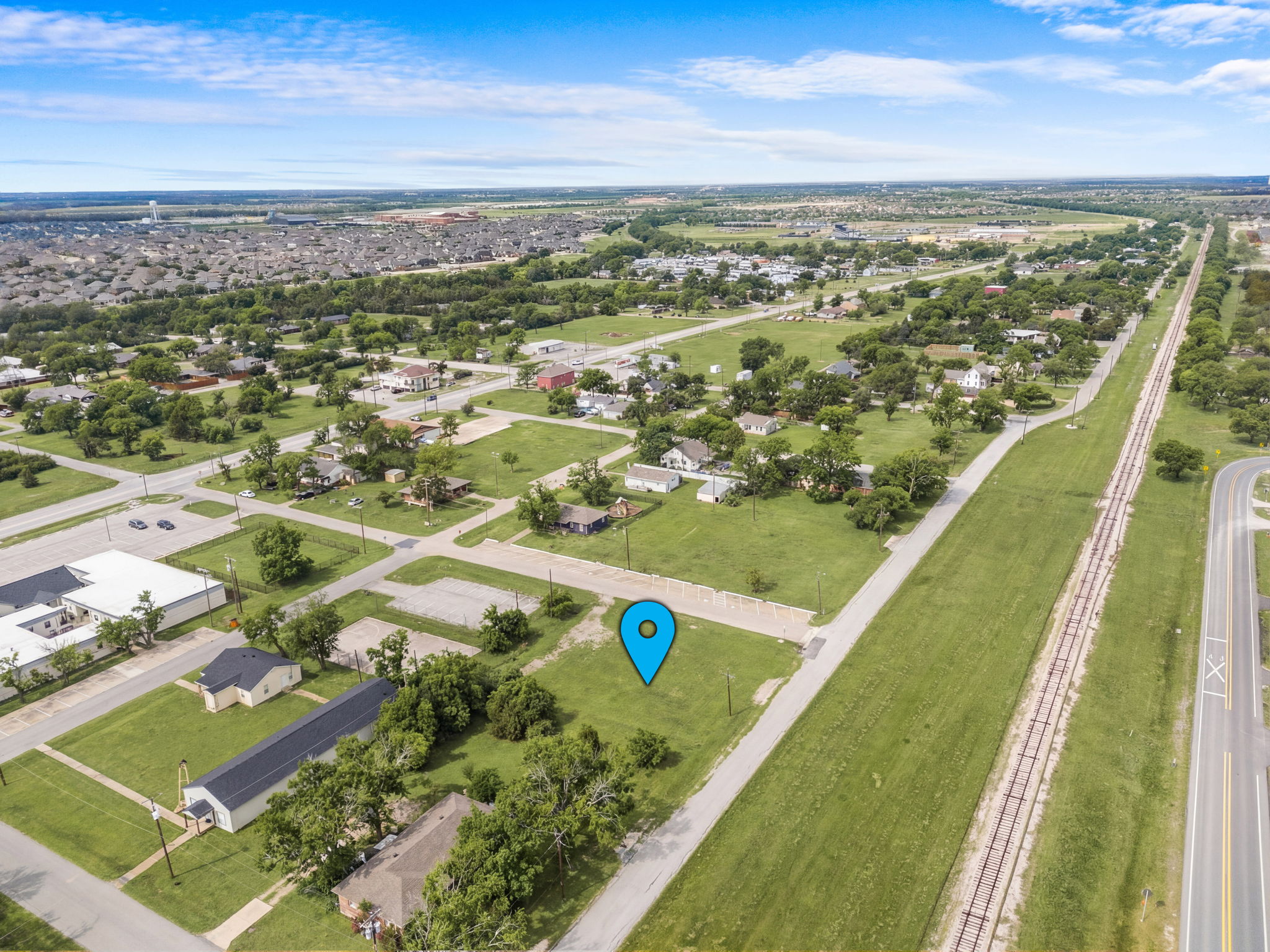 Mid-altitude aerial view of 211 N Riggins corner lot with pin marker